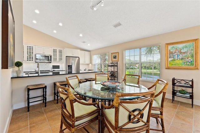 tiled dining space with vaulted ceiling and sink