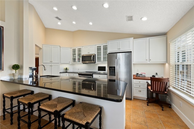 kitchen with a breakfast bar, kitchen peninsula, sink, appliances with stainless steel finishes, and white cabinetry