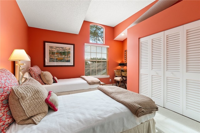 carpeted bedroom featuring lofted ceiling, a textured ceiling, and a closet