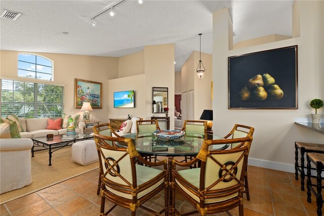 tiled dining area featuring a towering ceiling and track lighting