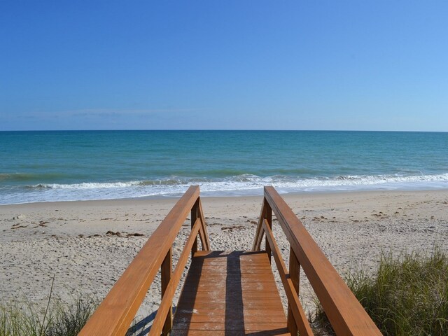 view of property's community featuring a beach view and a water view