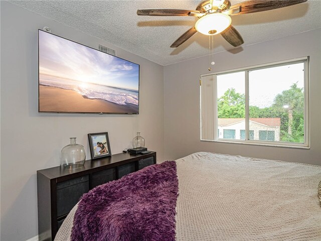 bedroom with ceiling fan, a textured ceiling, and carpet flooring