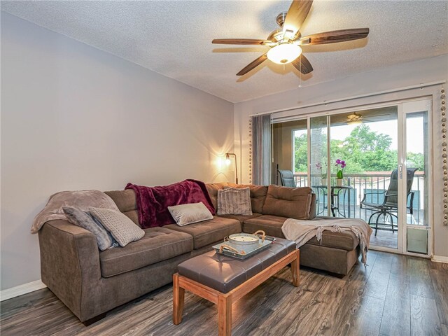 living room featuring dark wood-type flooring, ceiling fan, and a textured ceiling