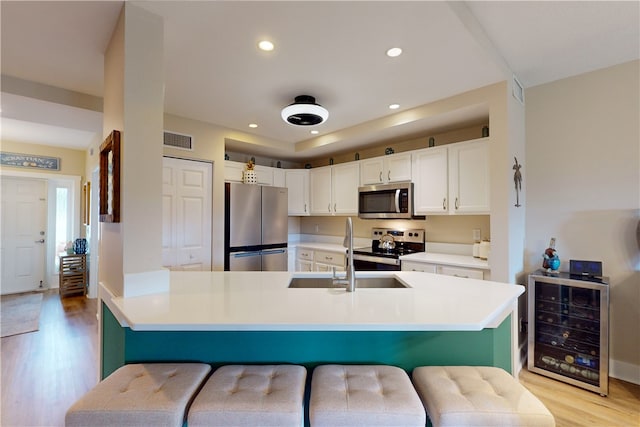 kitchen with stainless steel appliances, wine cooler, white cabinetry, and a breakfast bar area