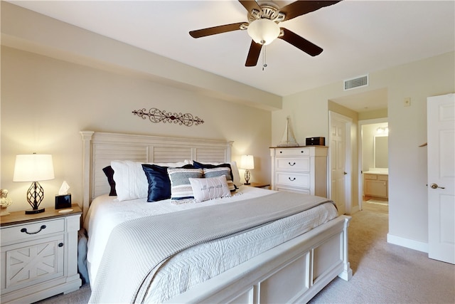 bedroom featuring light carpet, ensuite bathroom, and ceiling fan