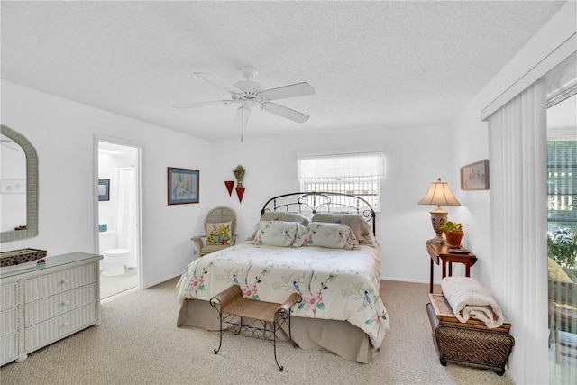 carpeted bedroom featuring ensuite bath, a textured ceiling, multiple windows, and a ceiling fan