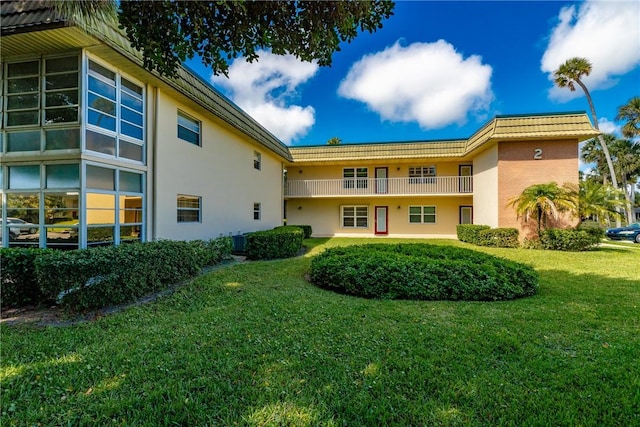 back of property with a lawn, stucco siding, a tiled roof, and central AC