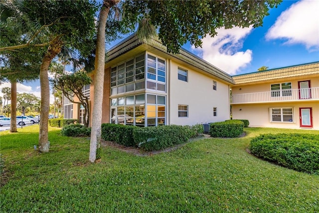 view of home's exterior featuring cooling unit, stucco siding, and a lawn