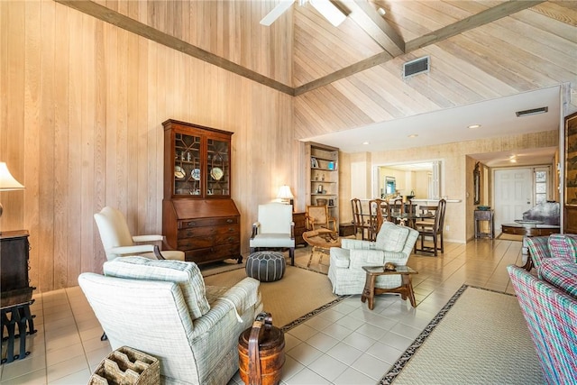 living room featuring ceiling fan, wood walls, a towering ceiling, light tile patterned flooring, and built in shelves