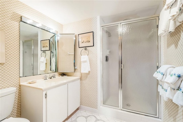 bathroom featuring a shower with door, toilet, and vanity