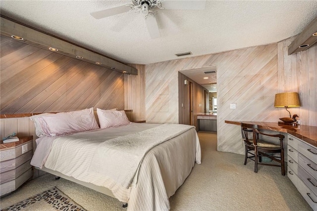 bedroom with ceiling fan, light carpet, wood walls, and a textured ceiling