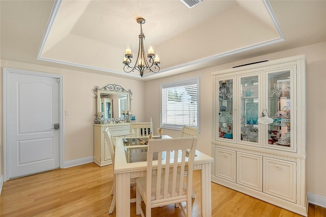 dining room with light hardwood / wood-style floors, a tray ceiling, and a chandelier