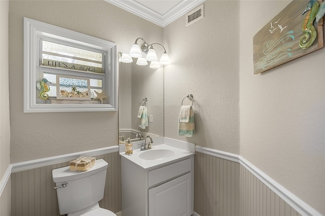 bathroom with toilet, vanity, and ornamental molding