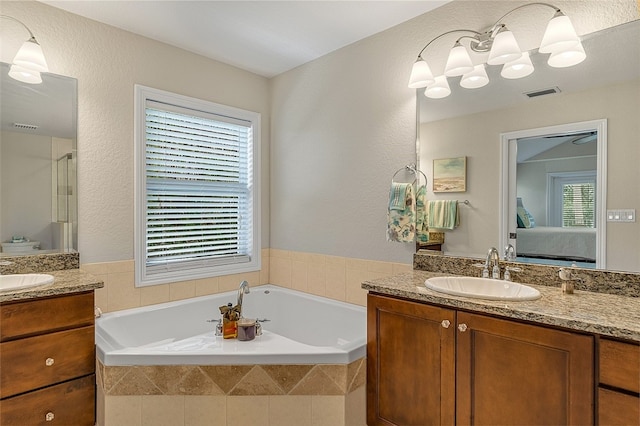 bathroom featuring tiled bath and vanity