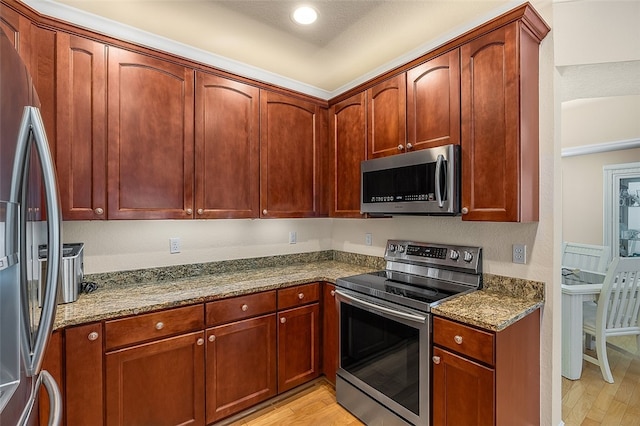 kitchen featuring appliances with stainless steel finishes, light hardwood / wood-style flooring, and light stone countertops