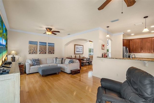 living room featuring ornamental molding, light hardwood / wood-style flooring, and sink