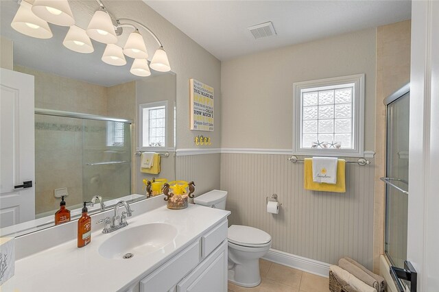 bathroom featuring toilet, tile patterned flooring, a shower with door, and vanity