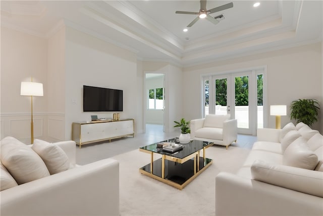 living room with french doors, ceiling fan, a raised ceiling, crown molding, and a high ceiling