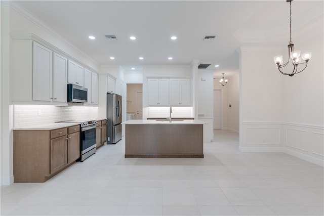 kitchen with a center island with sink, appliances with stainless steel finishes, hanging light fixtures, white cabinets, and decorative backsplash