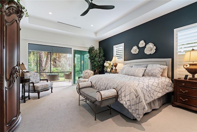 carpeted bedroom with ceiling fan, multiple windows, and a raised ceiling