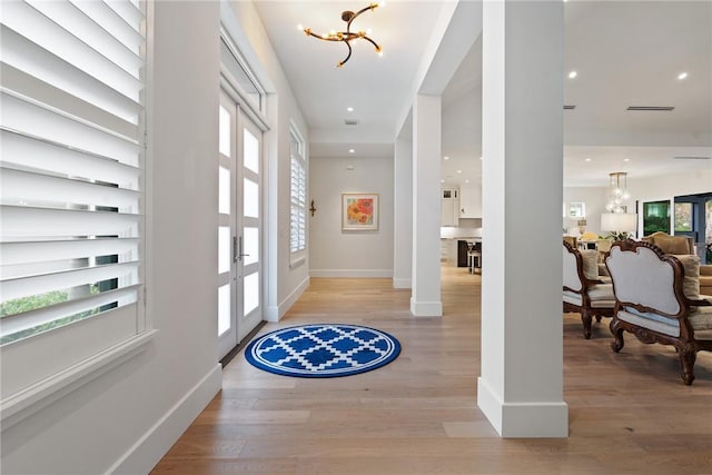 entryway featuring a healthy amount of sunlight, light hardwood / wood-style floors, and a notable chandelier