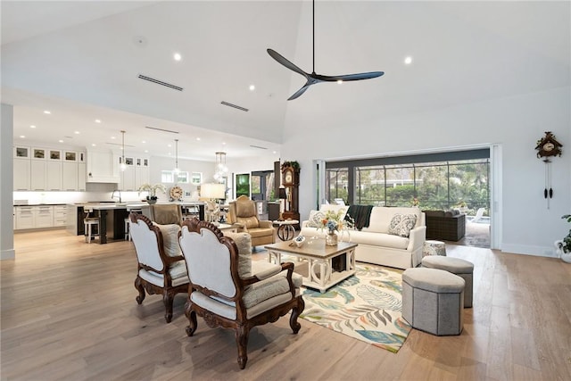 living room featuring light hardwood / wood-style floors, high vaulted ceiling, and ceiling fan