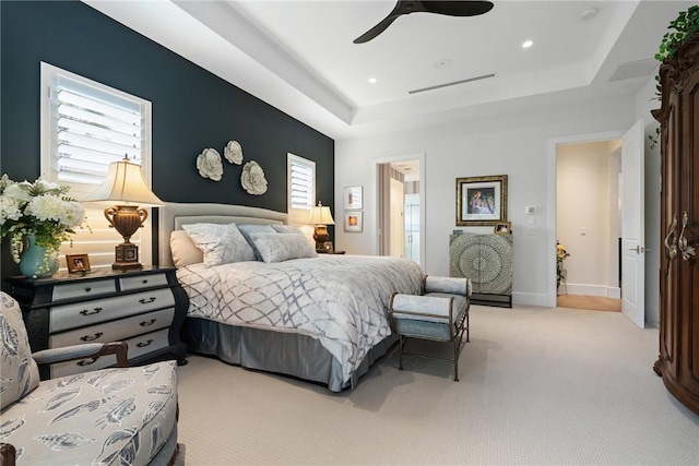 carpeted bedroom featuring ceiling fan, connected bathroom, and a tray ceiling