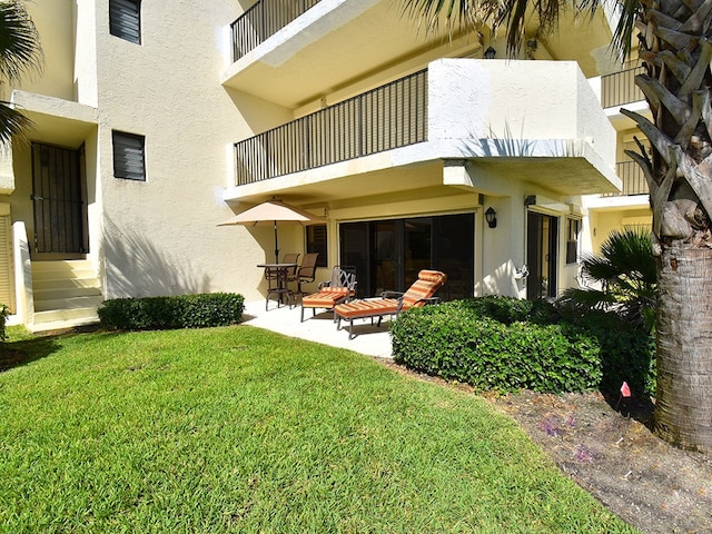 exterior space featuring a patio area, a lawn, and a balcony