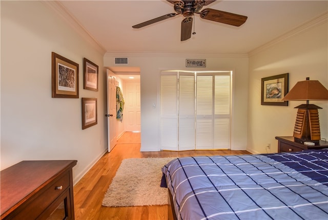 bedroom with a closet, light hardwood / wood-style floors, ceiling fan, and crown molding