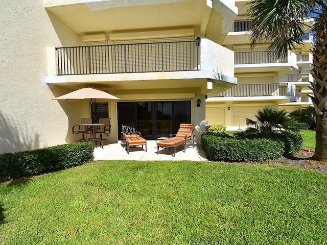 back of property with a lawn, a patio, and a balcony