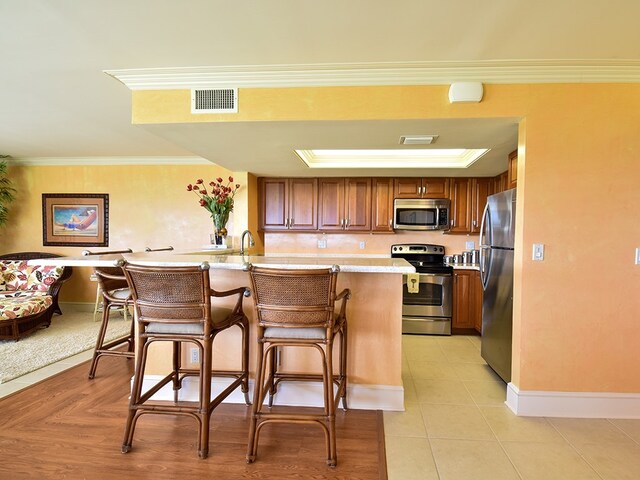 kitchen featuring a kitchen breakfast bar, appliances with stainless steel finishes, sink, and crown molding