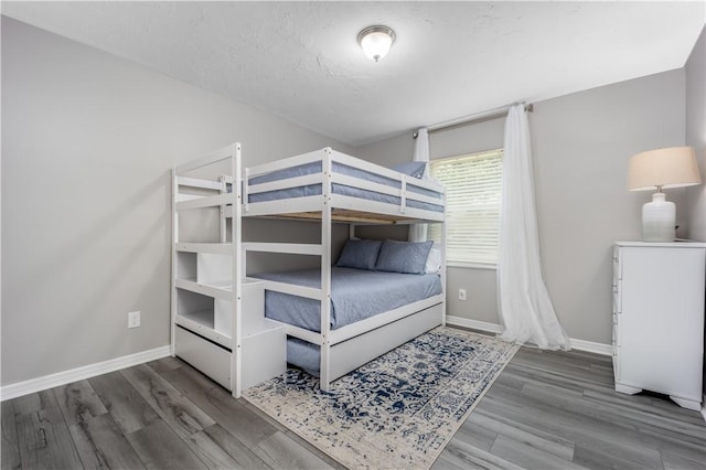 bedroom featuring a textured ceiling, baseboards, and wood finished floors