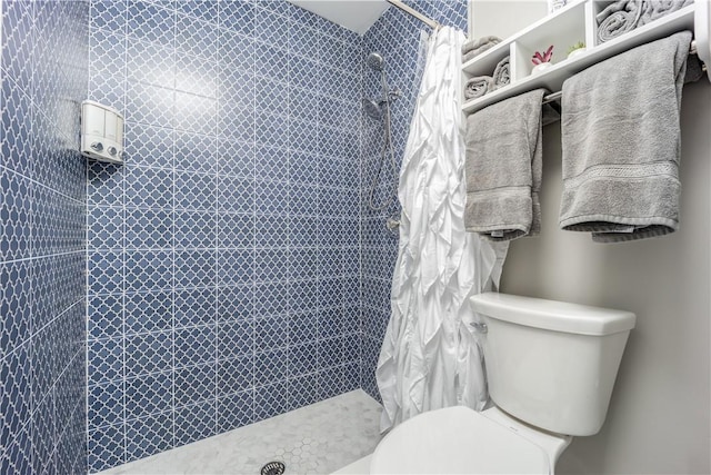 bathroom featuring a tile shower and toilet