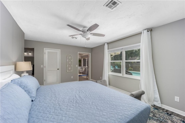 bedroom featuring ceiling fan, wood finished floors, visible vents, and baseboards