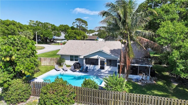 view of pool with a patio, a fenced in pool, a fenced backyard, a sunroom, and a lawn
