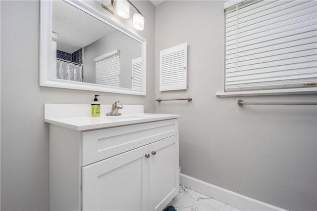 bathroom with marble finish floor, vanity, and baseboards