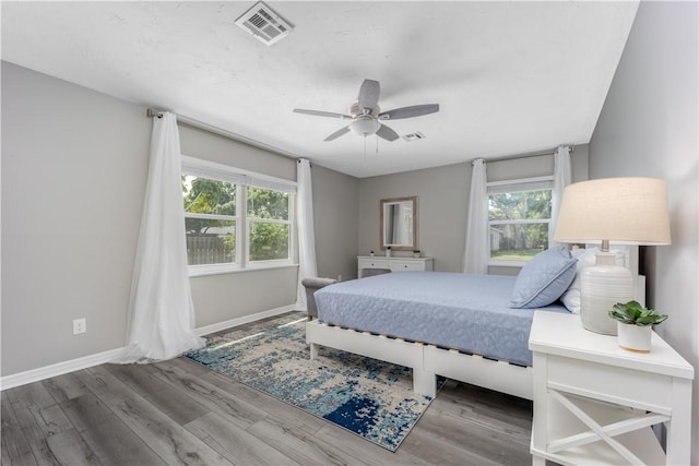 bedroom featuring visible vents, ceiling fan, baseboards, and wood finished floors