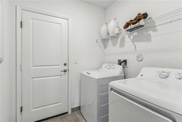 clothes washing area featuring light tile patterned floors and washing machine and clothes dryer