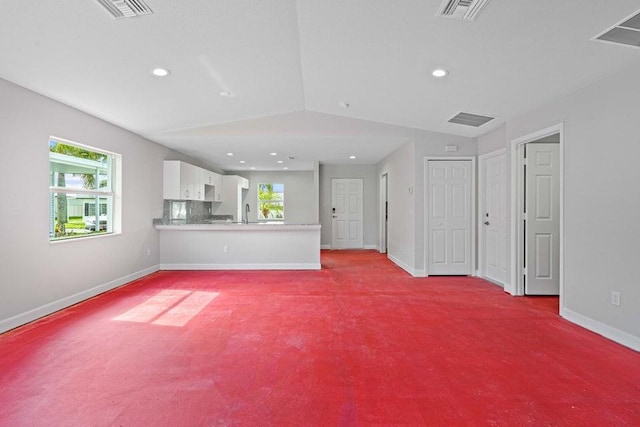 unfurnished living room with sink, light carpet, and vaulted ceiling