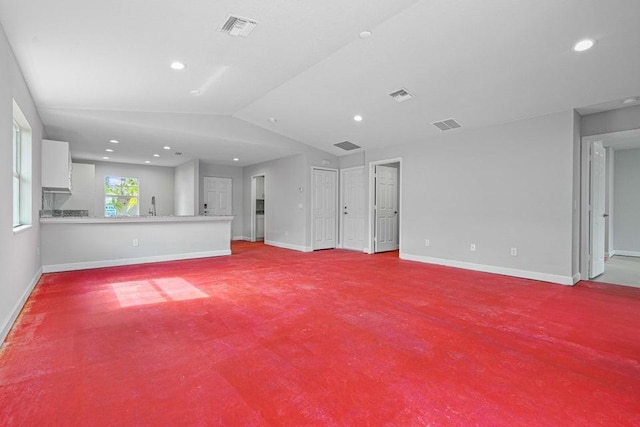 unfurnished living room featuring light colored carpet, sink, and vaulted ceiling