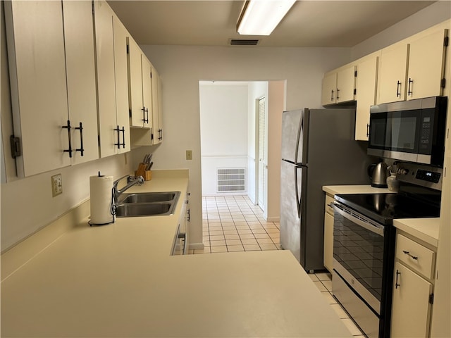 kitchen with light tile patterned flooring, appliances with stainless steel finishes, white cabinetry, and sink