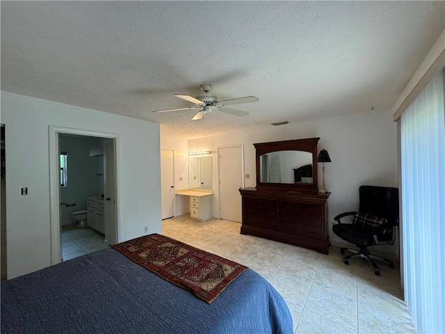 tiled bedroom featuring ensuite bathroom, ceiling fan, and a textured ceiling