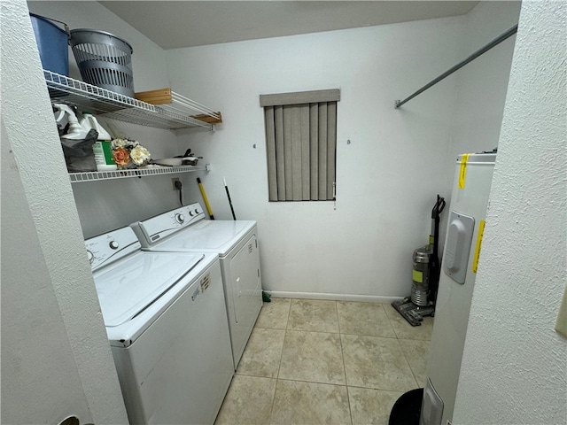 laundry room with electric water heater, washing machine and dryer, and light tile patterned floors