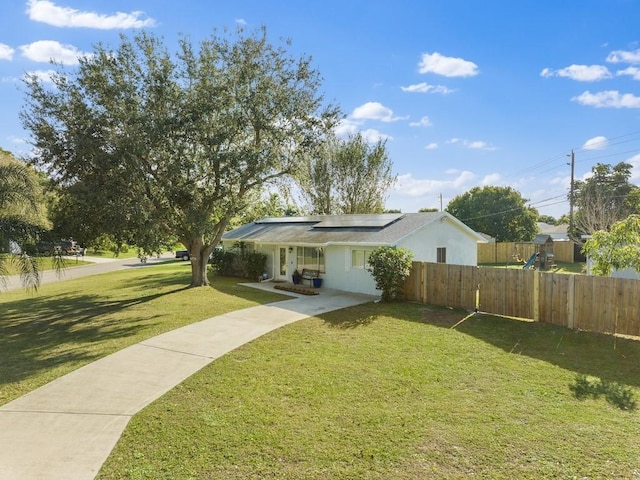 view of front of property with covered porch, solar panels, and a front lawn