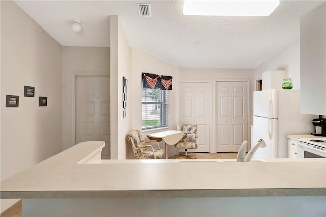 kitchen with white appliances, kitchen peninsula, and a textured ceiling