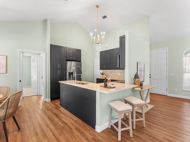 kitchen with stainless steel fridge with ice dispenser, sink, pendant lighting, and light wood-type flooring