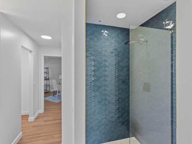 bathroom with hardwood / wood-style floors and tiled shower