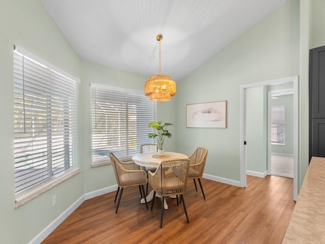 dining room with hardwood / wood-style flooring and vaulted ceiling