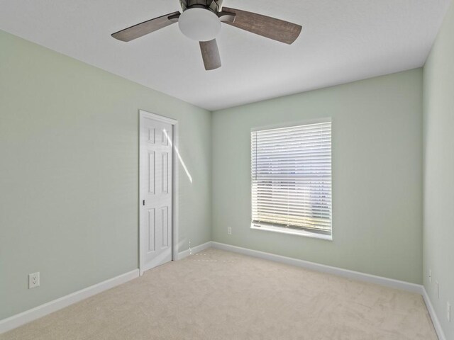 spare room with ceiling fan and light carpet