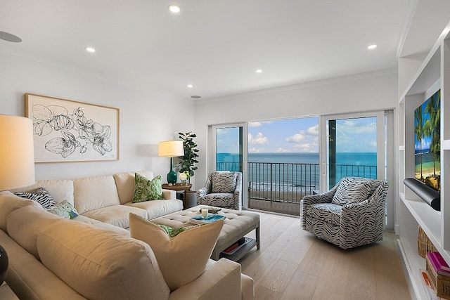 living room with ornamental molding, a water view, and light hardwood / wood-style floors